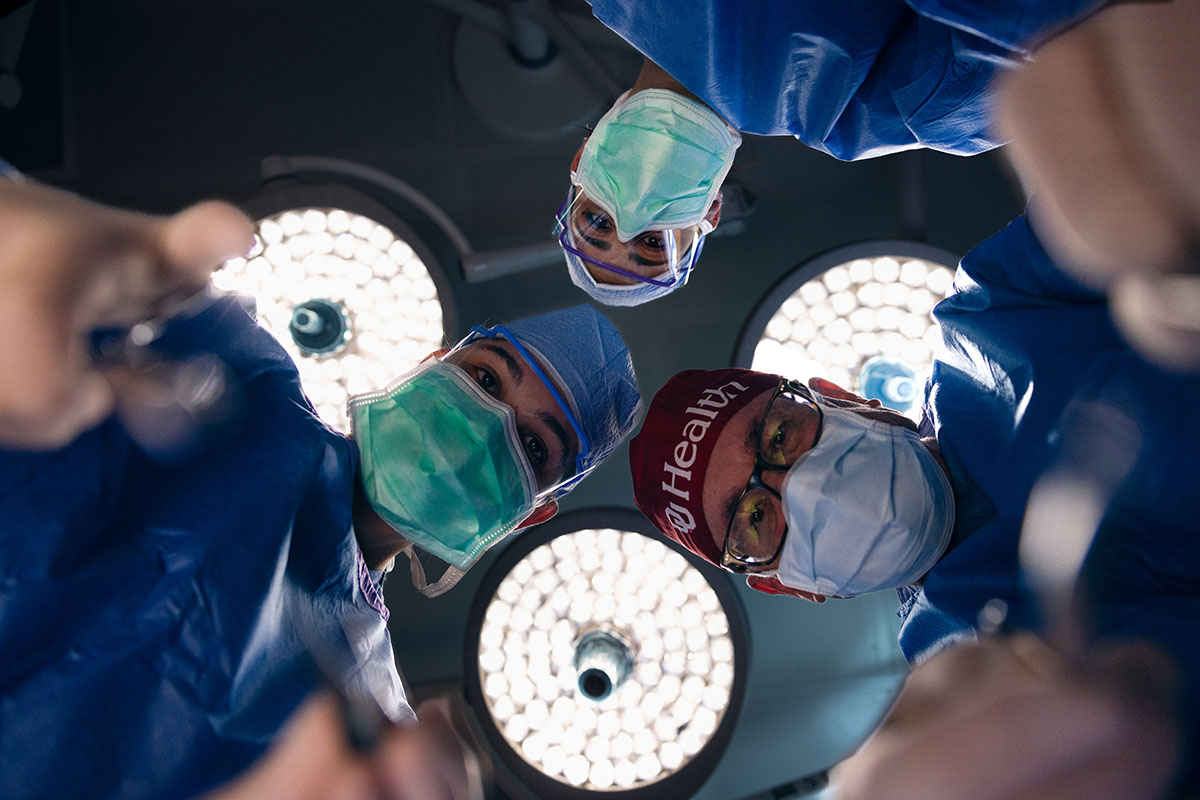 Doctors in full surgical operation garb looking into camera as from a patient POV